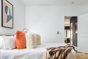 Ein Schlafzimmer mit einem Bett, Kissen, einer Decke und einem Bild an der Wand.