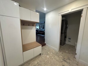 Un espace de vie compact comprenant un coin cuisine, un coin salon et un couloir menant à une salle à manger.