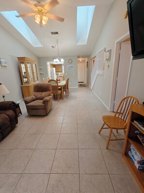 A spacious living area with a dining table, two sofas, a television, and a ceiling fan. - Parkside Paradise (Inverness)