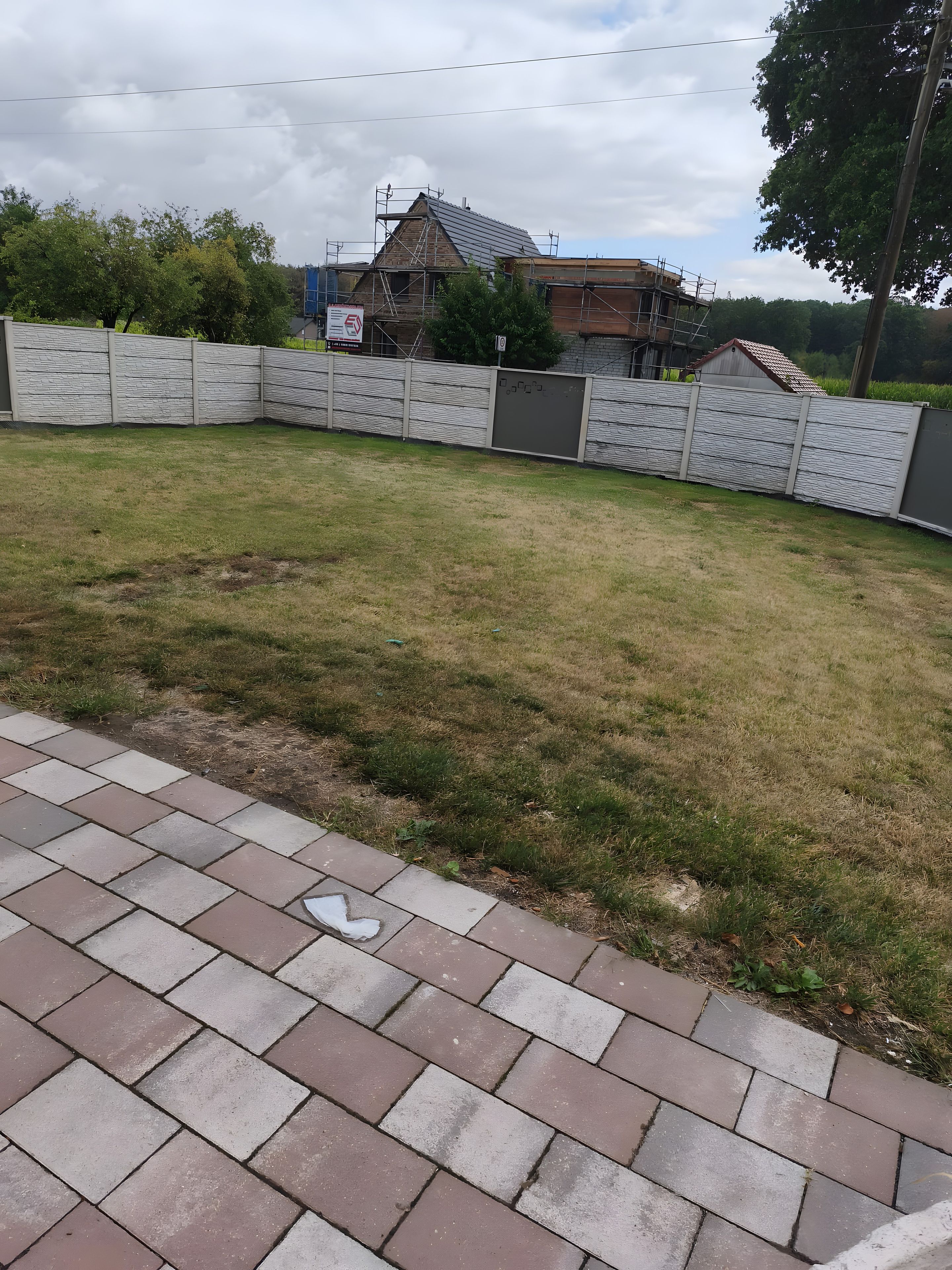 Laatoitettu terassialue, jossa on nurmikko ja metalliaita.