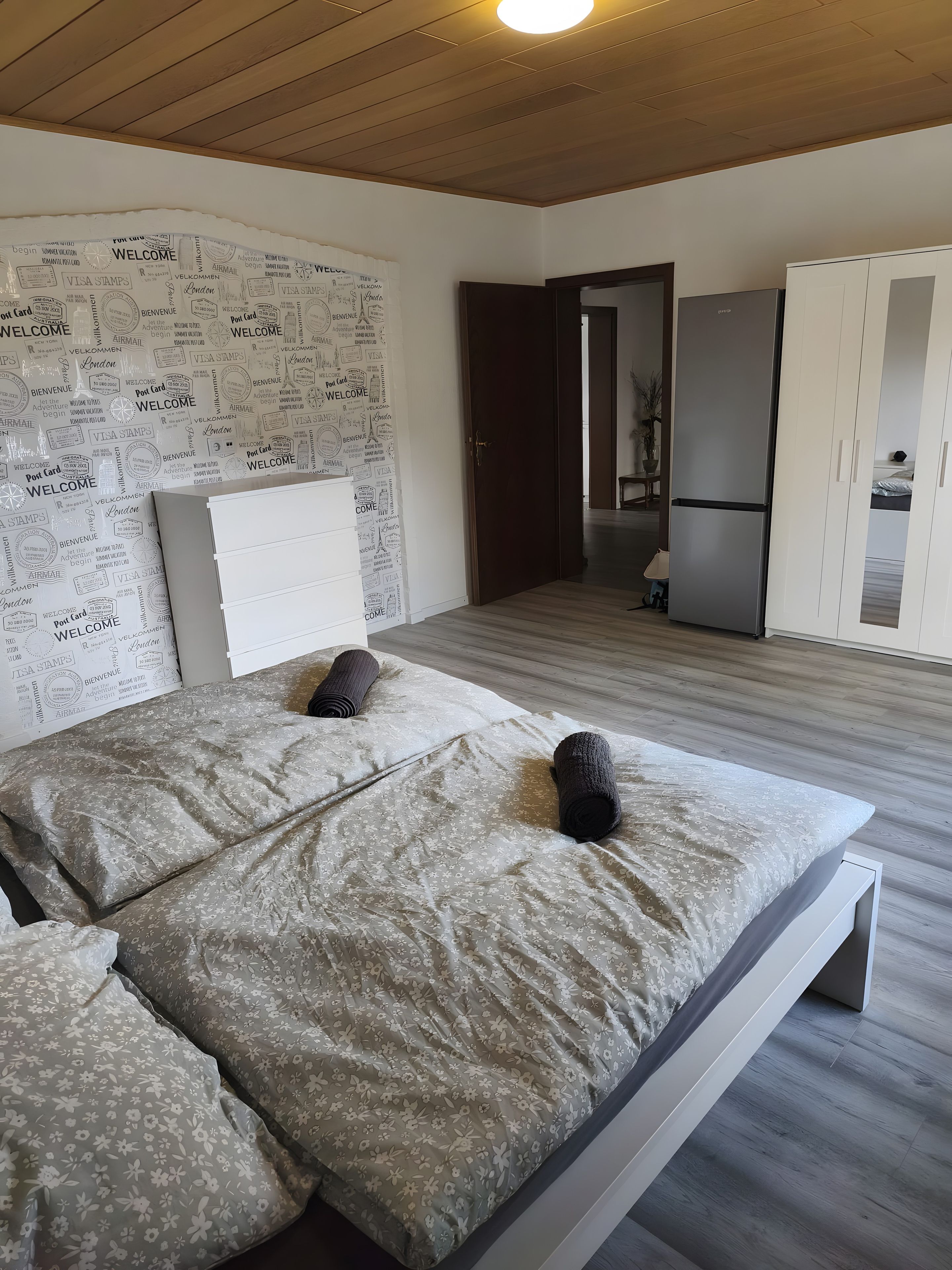 A bedroom with a bed, a wardrobe, and a door leading to a bathroom.