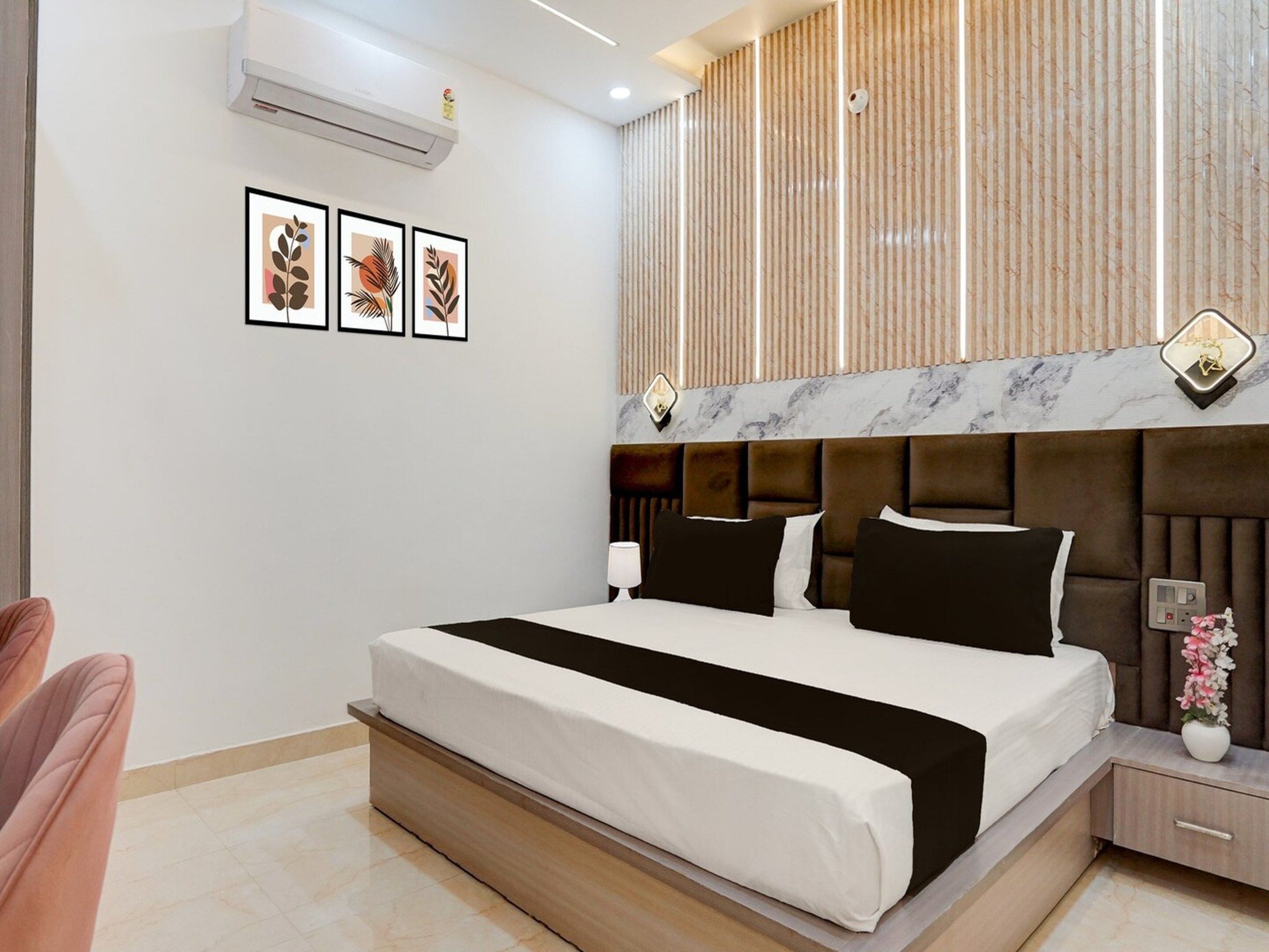 A modern hotel room with a large bed, a bedside table with a lamp, and a wall-mounted air conditioner.