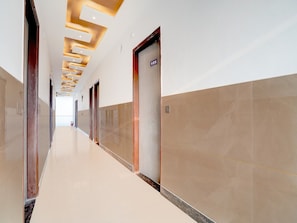A long, narrow hotel corridor with a polished floor, recessed lighting, and a series of doors on one side. - Classic G Grand Hotel (Sonepat)