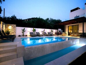 Ein moderner Poolbereich im Freien mit Liegestühlen und einer Steinmauer.