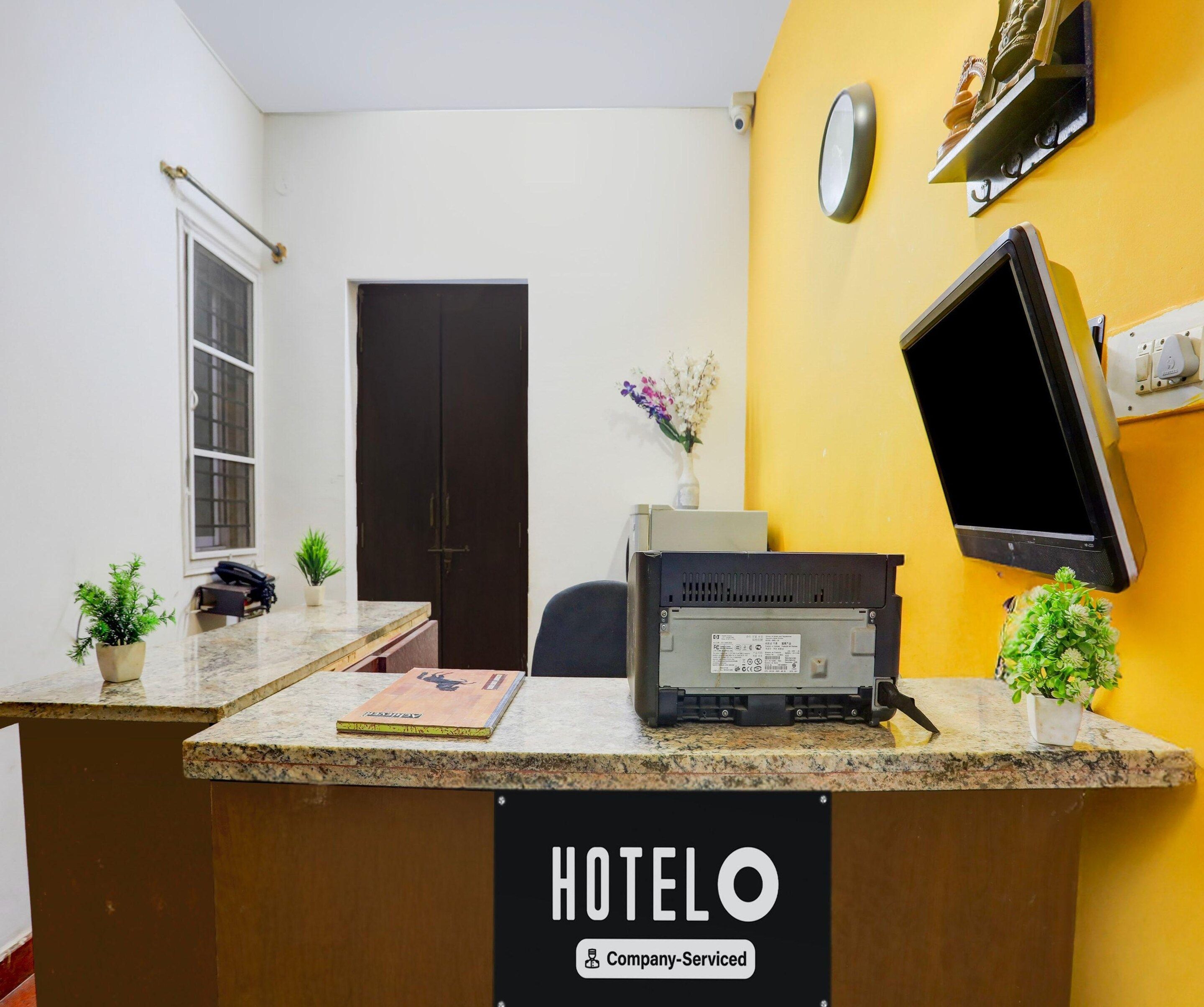 A hotel reception desk with a computer, a telephone, and a sign indicating it is company-serviced.