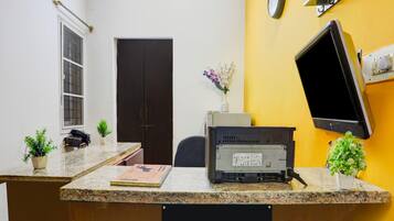 A hotel reception desk with a computer, a telephone, and a sign indicating it is company-serviced.