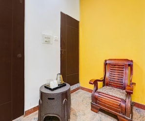 A room with a wooden chair, a small table with a tray, and a wall socket. - Classic Peaceful Stay (Bengaluru)