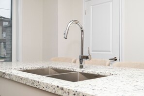 Une salle de bain avec un double lavabo, un robinet chromé et un comptoir en marbre.