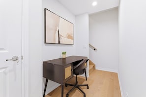 Ein moderner Arbeitsraum mit Schreibtisch, Stuhl und einem gerahmten Kunstwerk an der Wand.