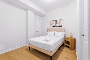 Ein Schlafzimmer mit einem Bett, einem Nachttisch, einer Lampe und zwei Wandbildern.