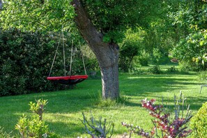 A tree with a swing hanging from its branches in a lush garden. - Thatched flat near Baltic Sea & golf course (Schashagen-Beusloe)