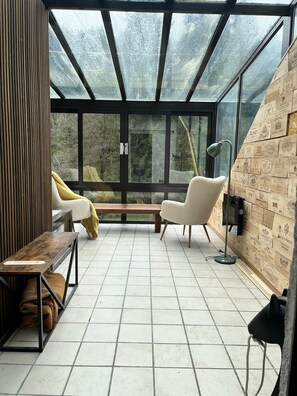 A modern interior with a glass ceiling, a wooden bench, a white armchair, and a floor lamp. - Cozy vacation home with a private forest, surrounded by nature and close to Houffalize. (Houffalize)