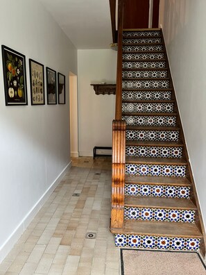 A staircase with patterned tiles and a wooden handrail, leading to a landing with a shelf. - Cozy vacation home with a private forest, surrounded by nature and close to Houffalize. (Houffalize)