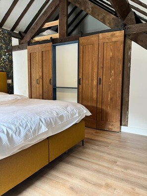 A bedroom with a bed, wooden wardrobe, and a sloped ceiling. - Cozy vacation home with a private forest, surrounded by nature and close to Houffalize. (Houffalize)