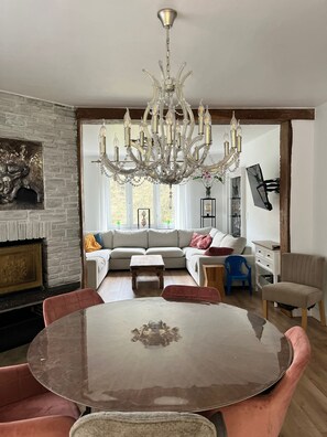A dining area with a round table and chairs, a chandelier, a sofa set, and a fireplace. - Cozy vacation home with private woods, surrounded by nature, near Houffalize (Houffalize)