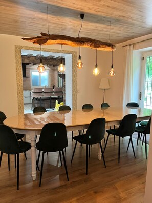 A dining area with a large table, black chairs, and hanging light fixtures. - Cozy vacation home with private woods, surrounded by nature, near Houffalize (Houffalize)