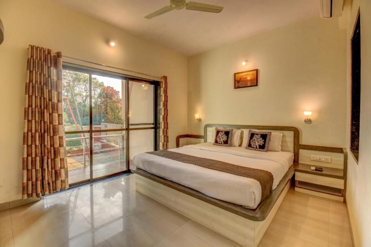 A bedroom with a bed, a nightstand, a ceiling fan, and a window with curtains.