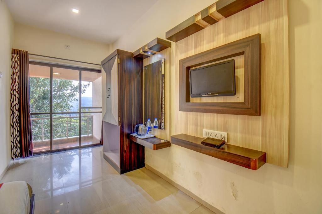 Una habitación de hotel moderna con un ventanal grande, un televisor de pantalla plana montado en la pared y una mesa consola de madera.