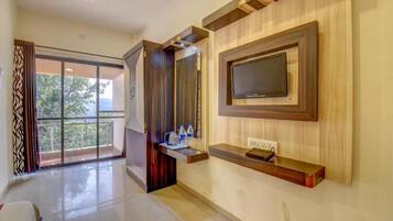 Una habitación de hotel moderna con un ventanal grande, un televisor de pantalla plana montado en la pared y una mesa consola de madera.