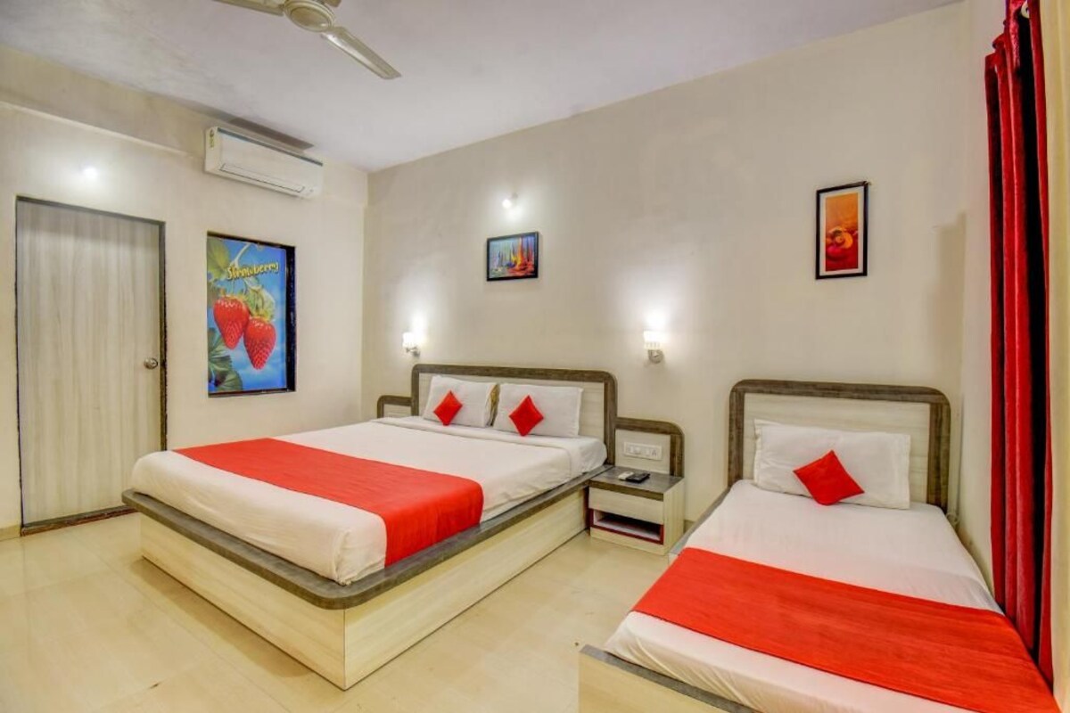 A hotel room with two beds, a ceiling fan, an air conditioning unit, and artwork on the walls.