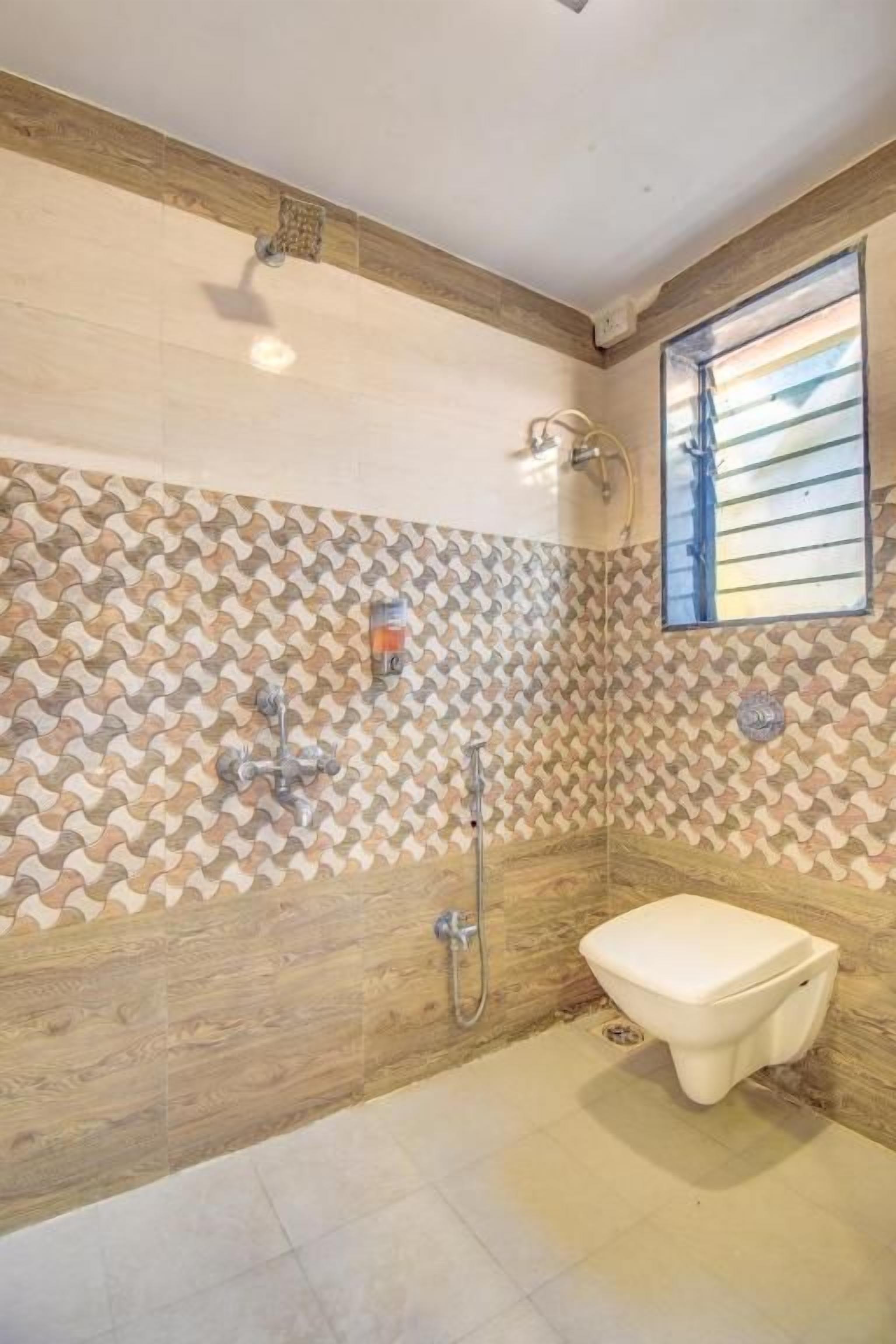 A bathroom with a shower, toilet, and a patterned wall.