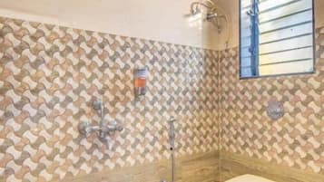 A bathroom with a shower, toilet, and a patterned wall.