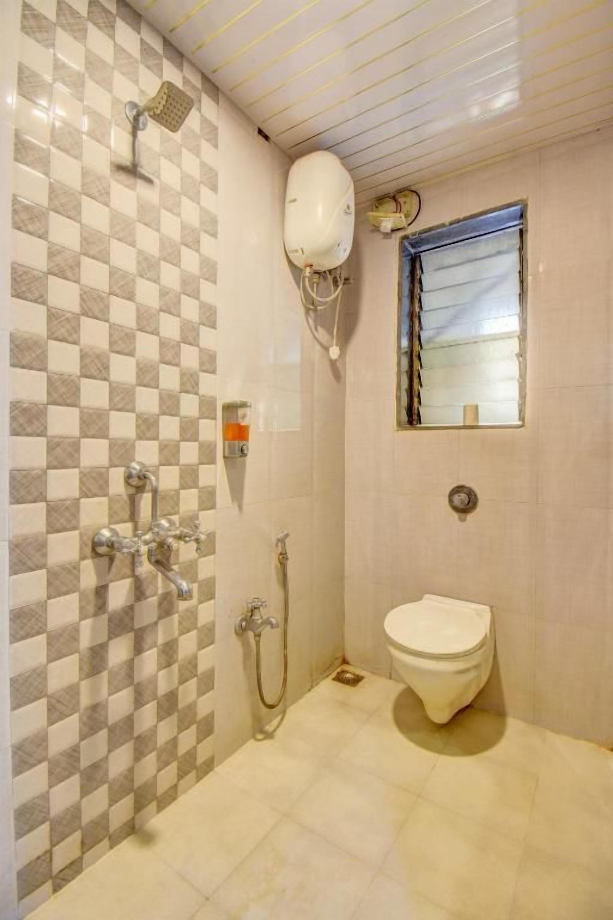 Un baño con pared de baldosas de cuadros, inodoro, ducha y espejo.