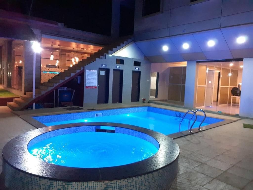 A swimming pool with a tiled edge, a staircase leading to an upper level, and a door with an emergency exit sign.
