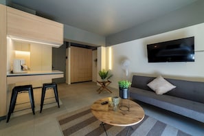 A modern living space with a kitchen area, a round coffee table, a sofa, and a TV mounted on the wall. - Studio with a terrace · Featured design (H05) (Providencia)