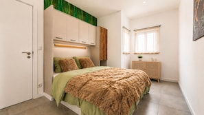A bedroom with a bed, a wardrobe, a bedside table with a lamp, and a window with curtains. - Stay at Ruby's Boutique townhouse for 6– 3 terraces, 4 min walk to the beach (Fuseta)