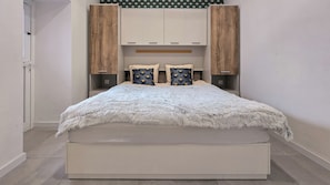 Ein modernes Schlafzimmer mit einem großen Bett, einer eingebauten Garderobe und dekorativen Wandverkleidungen.