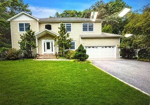 A two-story house with a front porch, a garage, and a well-maintained lawn. - Fabulous 4-bedroom house with AC in charming Dix Hills (Dix Hills)