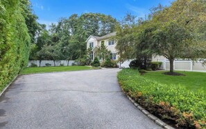 A residential driveway leading to a two-story house with a front yard and a tree. - Fabulous 4-bedroom house with AC in charming Dix Hills (Dix Hills)