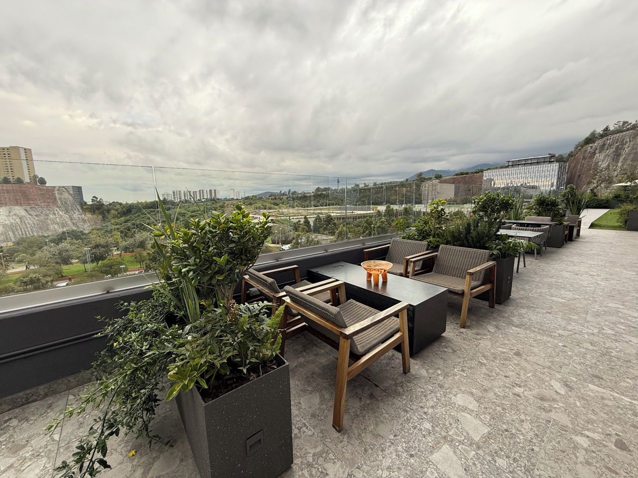 En takterrass med utomhusmöbler, krukväxter och utsikt över stadsbilden.