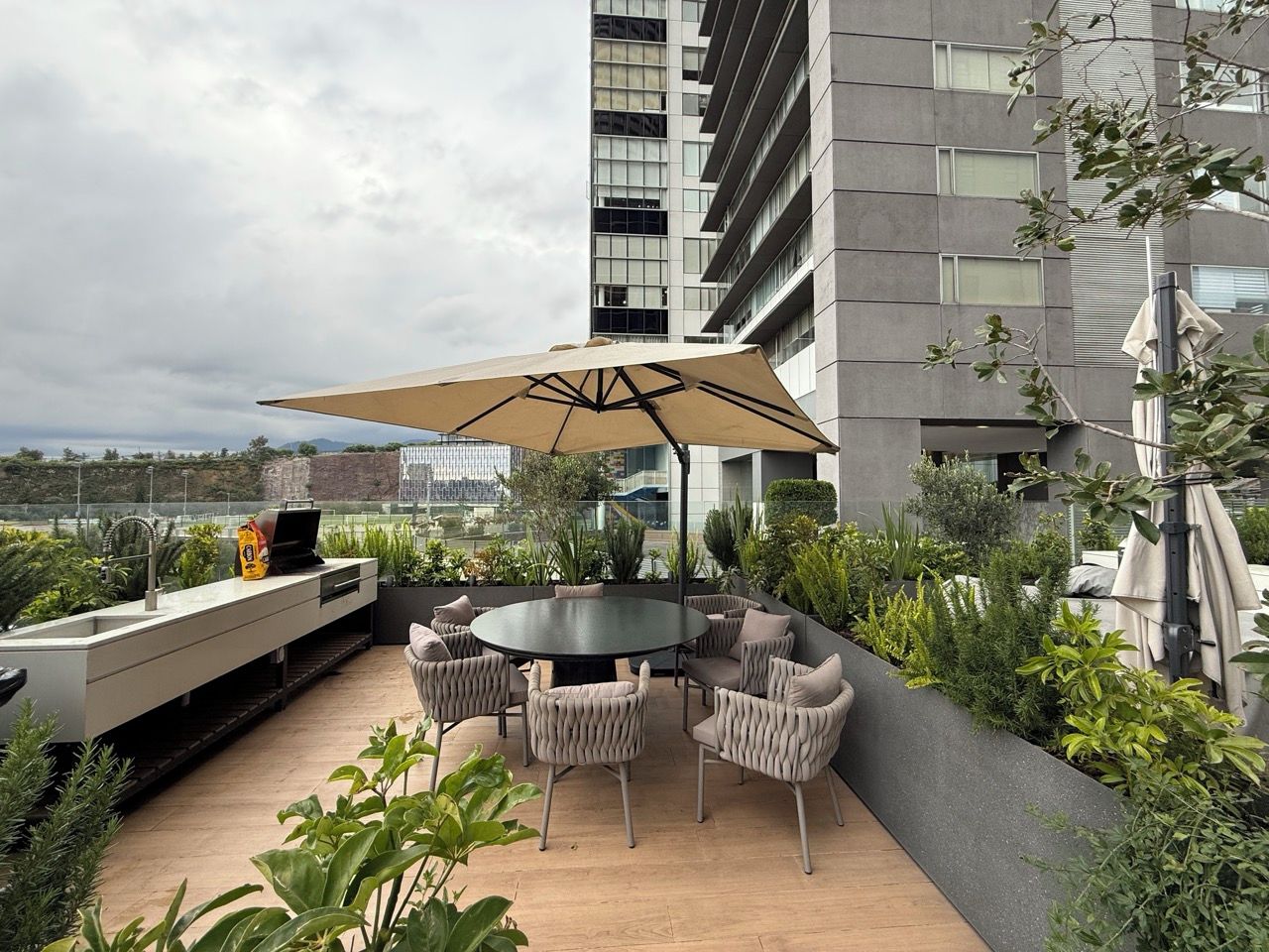Une terrasse extérieure avec une table ronde et des chaises, un barbecue et une vue sur le paysage urbain.