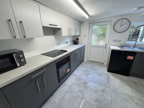 A modern kitchen with grey cabinets, a built-in oven, a microwave, and a sink. - Pet-friendly 3-bed house near Framlingham Castle, sleeps 5 (Framlingham)