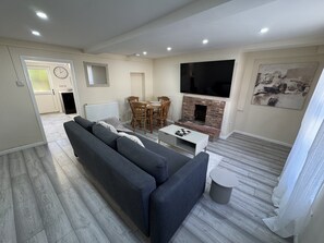 Een moderne woonkamer met een bank, een bijzettafeltje en een open haard.