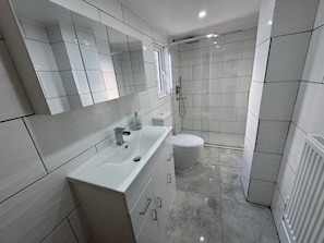 A modern bathroom with a large mirror, a sink, a toilet, and a shower area. - Pet-friendly 3-bed house near Framlingham Castle, sleeps 5 (Framlingham)