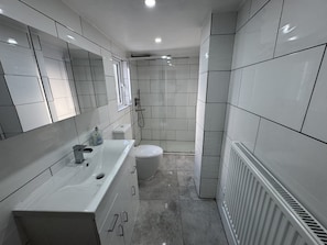 Een moderne badkamer met een wit wastafelmeubel, spiegel en toilet.