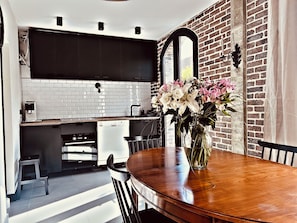 A modern kitchen with white subway tiles, a brick wall, and a dining area with a wooden table and chairs.