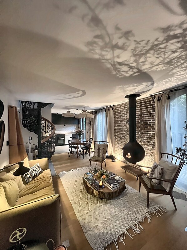 A modern living room with a sofa, coffee table, and a fireplace. There is a staircase leading to an upper level. - Vrbo Property (Bullion)