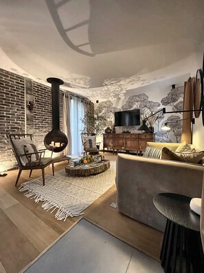 A modern living room with a fireplace, a television, and a cozy seating area. - Vrbo Property (Bullion)