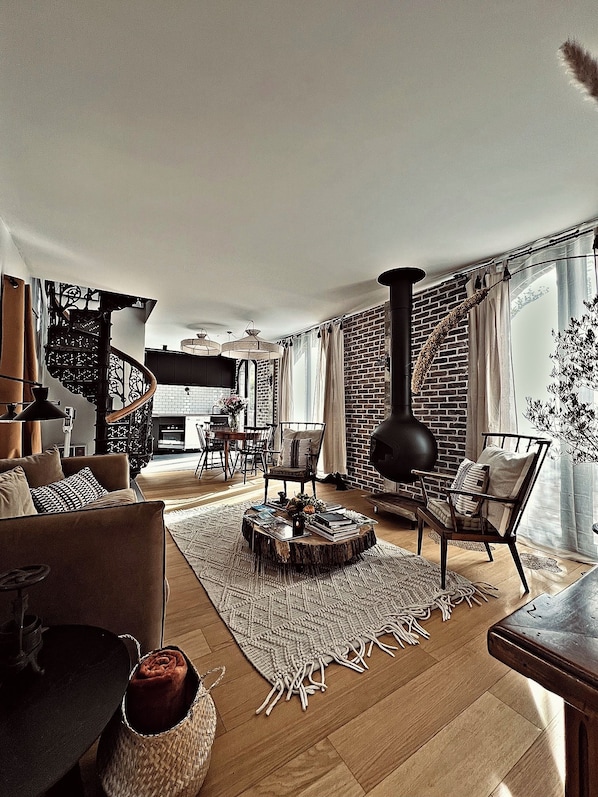 A modern living room with a fireplace, a spiral staircase, and a dining area.
