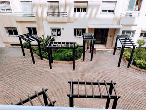 A courtyard with outdoor seating and a building with balconies. - Apparently, the Grand Hassan II Mosque is 2 minutes from the sea. (Dar-el-Beida)
