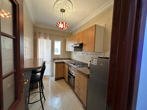 A kitchen with granite countertops, a gas stove, a refrigerator, and wooden cabinets. - Apparently, the Grand Hassan II Mosque is 2 minutes from the sea. (Dar-el-Beida)