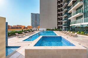 Ein Pool auf dem Dach mit Liegestühlen und Blick auf die umliegenden Gebäude.