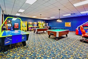 Ein Raum mit Billardtischen, Spielautomaten und einem gemusterten Teppich.