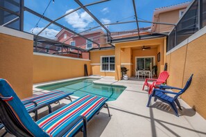 Ein überdachter Außenbereich mit Pool, Liegestühlen und einem Patio-Tisch.