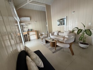 Ein modernes Wohnzimmer mit einer Couch, einem Couchtisch und einem Essbereich mit Schrank und Stühlen.