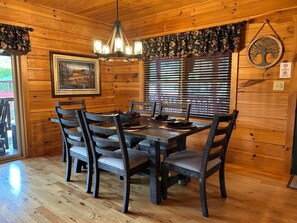 A wooden dining room with a table and chairs, a chandelier, and a window with blinds. - Chestnut Lodge-Fantastic Cabin! Easy Access, Views (Maggie Valley)